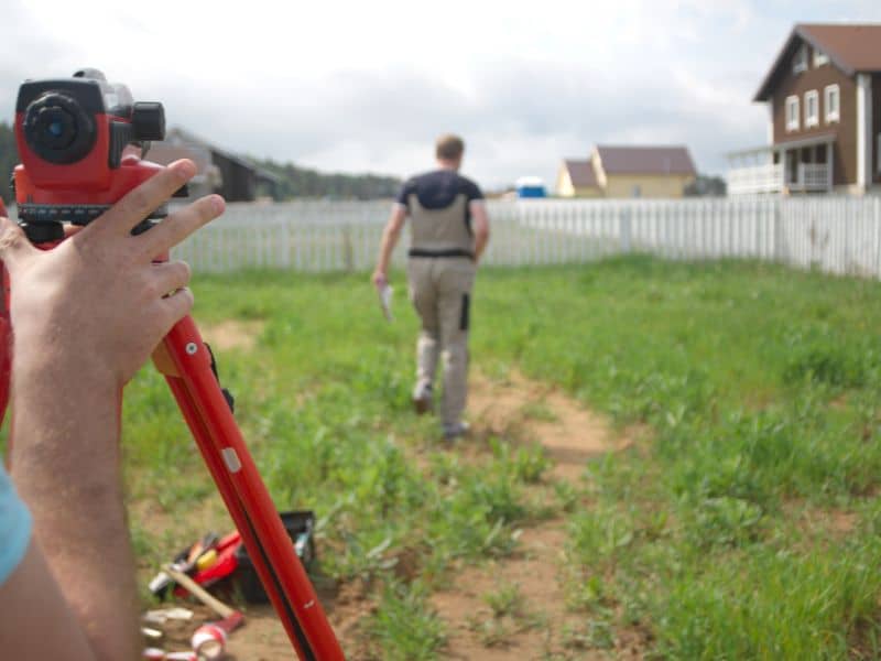 Surveyor checking a residential property boundary near fence lines