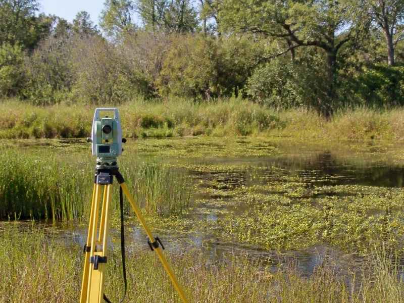 Surveying equipment positioned beside a natural wetland area in Orlando, Florida.